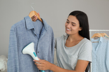 Poster - Woman steaming shirt on hanger at home