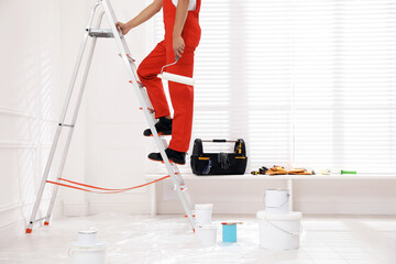 Wall Mural - Worker with roller climbing up ladder indoors, closeup. Space for text