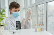 © Anna - Close up image of boy in mask puting on gloves before chemistry experiments with microscope, curiosity of young scientist, educational concept