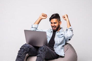 Wall Mural - Happy man sitting on the floor with a laptop over a white background