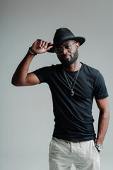 Handsome african american man in a hat holds his hand to her and looks into the camera with a hand in his pocket