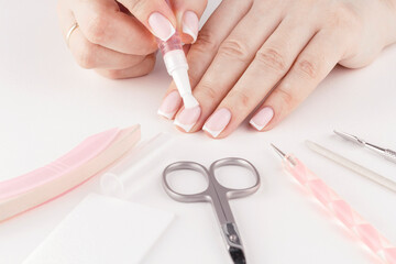 Wall Mural - Female hands with pastel trendy French manicure moisturizing cuticle. Close up, top view.