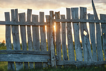 Old wooden plank fence of vertical flat boards at sunset