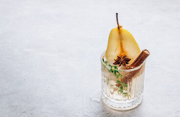 Wall Mural - Traditional autumn spicy cocktail with pear. Cold pear white tea or mulled wine with cinnamon, thyme and anise on the light beige background