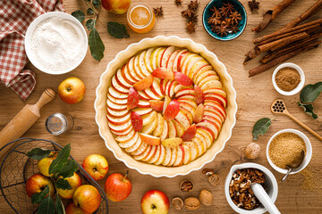 Wall Mural - Cooking Thanksgiving autumn apple pie with fresh fruits and walnuts on wooden table, top view