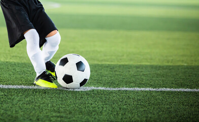 Wall Mural - Selective focus to football with motion blur of kid soccer player shoot it on artificial turf. Soccer player training for football match.