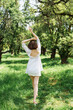 © LIGHTFIELD STUDIOS - Back view of brunette woman in white dress walking in park
