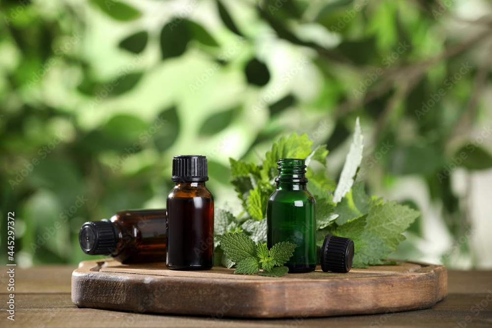 Glass bottles of nettle oil and leaves on wooden table against blurred background, space for text - obrazy, fototapety, plakaty 
