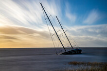 Sinking Sailboat Close To Shore With Beautiful Wispy Clouds In The Background