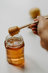 Sticker - Vertical shot of a hand holding wooden honey dipper stick on a jar