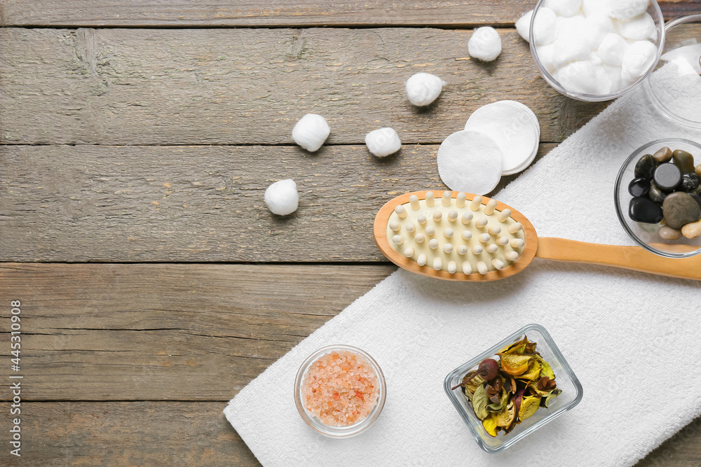 Massage brush and different bath supplies on wooden background