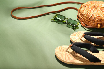 Flip-flops, sunglasses and bag on color background