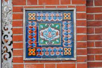 Wall Mural - Fragment of the decoration of the facade of an old building in the form of ceramic tiles with a geometric pattern