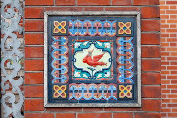 Wall Mural - Fragment of the decoration of the facade of an ancient building in the form of ceramic tiles with the image of the Phoenix Bird