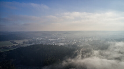 Poster - Aerial view of white mist covering agricultural fields and dense trees