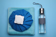 Bottle of water, cold compress and towel on light blue background, flat lay. Heat stroke treatment