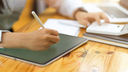 Cropped shot of female hands using tablet and stylus pen while calculating