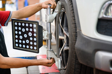 Auto service mechanic installing wheel alignment sensor on tire during vehicle suspension alignment adjustment. and set the car wheel center at the auto repair station