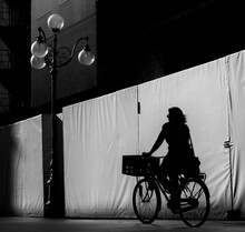 Rear View Of Silhouette Man With Bicycle On Street