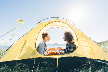 couple sitting in yellow camping tent and eating pizza.