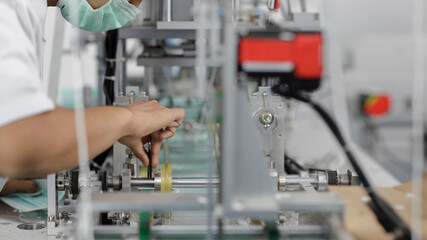 Asian worker hands inspecting quality of mask and medical face mask production line, Industry and factory concept.