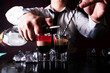 Barman preparing cocktail shots at the bar counter. Barman mixing drinks at the night club