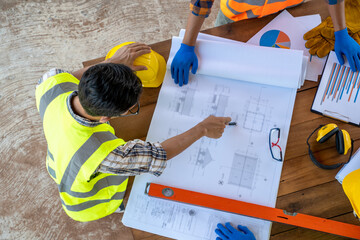 Aufkleber - Top view of Engineers or architect holding a pen with drawings in construction on blueprints in construction site for discussing.