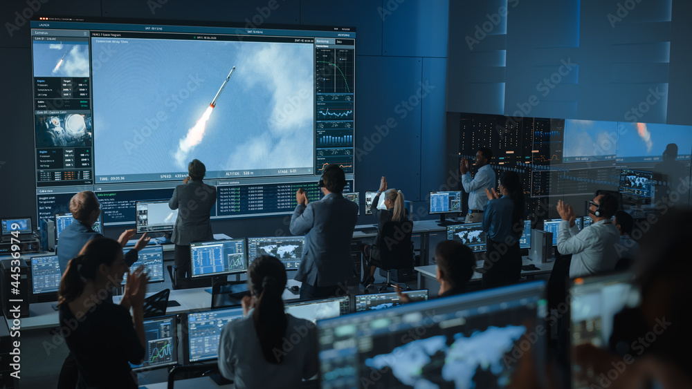 Group of People in Mission Control Center Witness Successful Space Rocket Launch. Flight Control Employees Sit in Front Computer Displays and Monitor the Crewed Mission. Team Stand Up and Clap Hands. - obrazy, fototapety, plakaty 