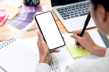 Wall Mural - woman hands using smartphone and writing note while working at office.