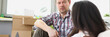 © H_Ko - Man and woman sitting on floor with laptop behind them boxes