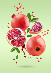 Wall Mural - A ripe pomegranate with seeds and leaves flying in the air. Background with pomegranate fruit.