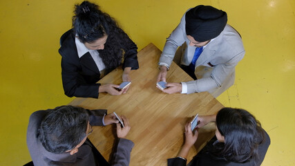 Poster - Group of Indian people sitting around the table with their smartphones in the office