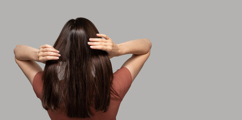 Wall Mural - Banner with turned back girl touching her hair on light background