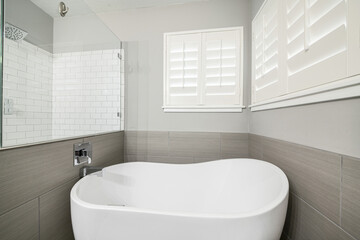 Poster - Bath tub in a bathroom with gray walls, a large mirror and windows