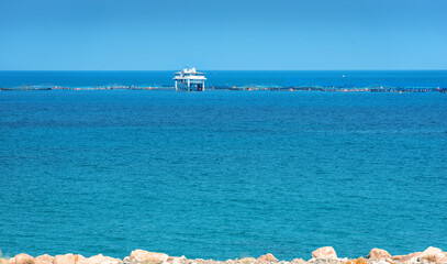 Fish farm growing sea bass and dorado fish in Mediterranean sea, view from the shore at Limassol cargo port