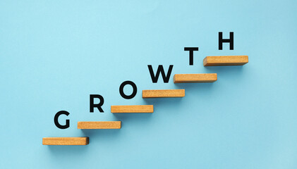 Wall Mural - Growth word on staircase on blue background. Increasing business, success process concept. Copy space