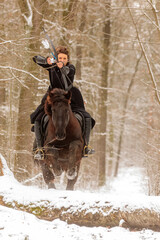 Wall Mural - a beautiful woman rides through the snowy countryside and points her bow straight ahead