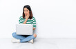 © luismolinero - Young Vietnamese woman with a laptop sitting on the floor isolated on white wall surprised and shocked while looking right