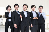 Fototapeta  - 笑顔の５人の男女の会社員がで並んで立ち中央のビジネスウーマンが手を差し伸べる