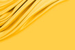 Beautiful elegant wavy yellow satin silk luxury cloth fabric texture with monochrome background design. Copy space