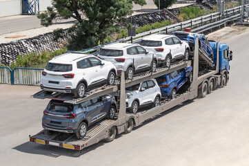 car carrier trailer transporting new automobiles on road