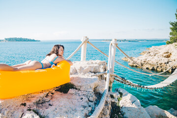 Wall Mural - smiling woman at sea beach on yellow air sofa