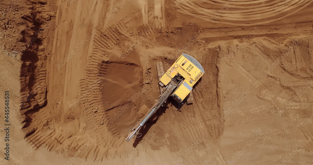 Aerial view of a digger, tracked excavator at work on a construction. - obrazy, fototapety, plakaty 