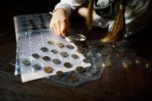 Cute Cute European Girl Child In Glasses With Magnifying Glass Looks At Coins, Concept Children And Financial Literacy, Children And Money, Coin Collecting And Numismatics, Dark Style
