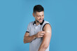 © New Africa - Vaccinated man with medical plaster on his arm against light blue background