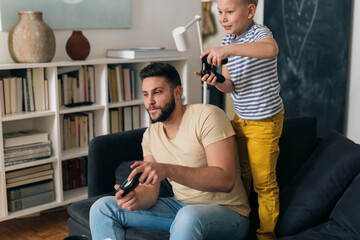 Wall Mural - father and son playing video games with controllers at home