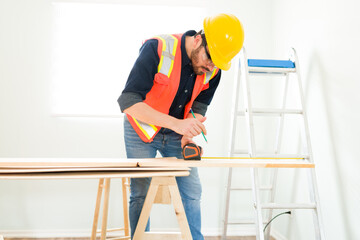 Wall Mural - Male engineer using a measuring tape to cut wood