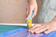 © zergsv - Home craft concept photo - woman hands, cutting textile for patchwork or quilt  on a mat with rotary cutter and ruler.