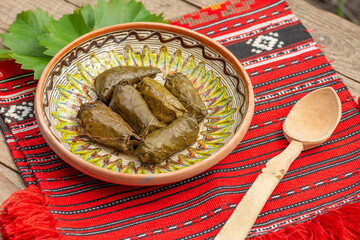 Wall Mural - Close-up shot of shrub dolma in the wooden plate and a wooden spoon on red traditional carpet