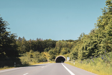 Wall Mural - Beautiful view of a country road leading to a tunnel surrounded by green nature